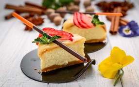 Два куска чизкейка с клубникой на столе с палочками