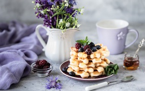 Вафли с ягодами черники и ежевики на столе с букетом