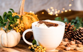 Чашка горячего маршмеллоу с корицей на столе с тыквой и шишками