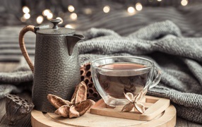 Чашка чая на столе с чайником и теплым пледом