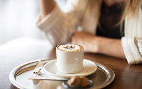 Чашка капучино с корицей на столе в кафе