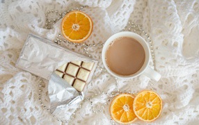 Чашка какао, шоколад и апельсин на белом пледе