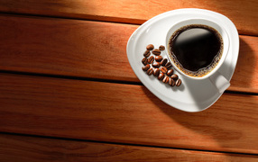 Чашка кофе на тарелке с зернами на деревянном столе