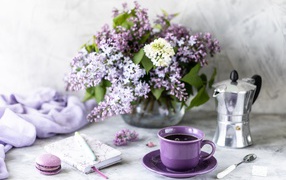 Чашка кофе на столе с блокнотом и букетом сирени в вазе