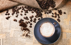 Чашка кофе на столе со старыми газетами и зернами