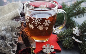 Стеклянная чашка чая на столе с ветками ели и шарфом 