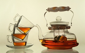 Стеклянный чайник с чашками на белом фоне