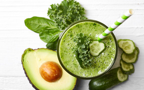 Зеленый смузи на столе с огурцом, авокадо и зеленью