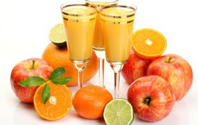 Сок в фужерах на столе с яблоками и мандаринами 