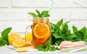 Лимонад на столе с лимоном и листьями мяты 