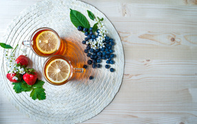 Чай с лимоном на столе с ягодами клубники и черники