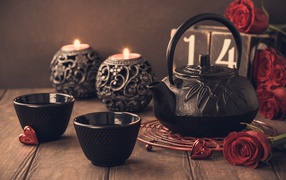 Две чашки чая на столе со свечами и красными розами