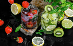 Два стакана мохито на столе с мятой, лимоном и клубникой 