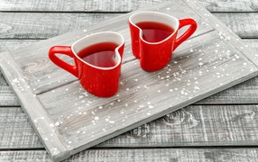 Две красные чашки в форме сердца на столе 