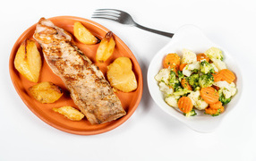 A piece of baked fish on a plate with vegetables