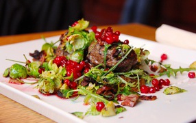 Кусок жареного мяса с салатом на тарелке