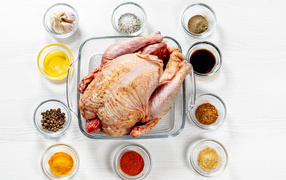 Свежая курица на противне на столе со специями 