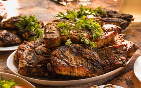 Много жареного мяса на тарелке с петрушкой 