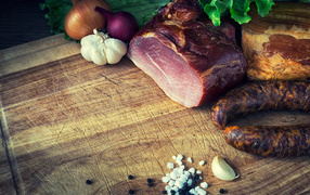 Мясные продукты на столе со специями, луком и чесноком 