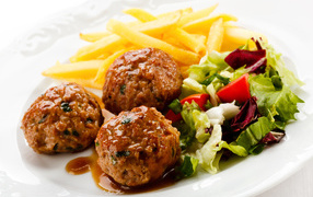 Фрикадельки с салатом и картофелем фри на белой тарелке