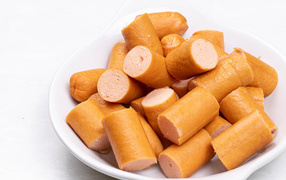 Молочные сосиски кусочками на белом фоне