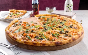 Большая аппетитная пицца с маслинами на столе в кафе