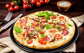 Tasty pizza with sausage, cheese and tomatoes on the table