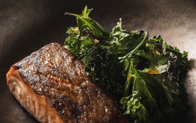 Кусок запеченной рыбы с листьями салата в сковороде 