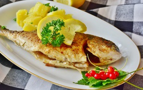 Жареная рыба с лимоном на тарелке с картофелем