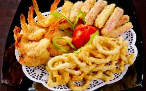 Морепродукты в кляре на тарелке с помидором