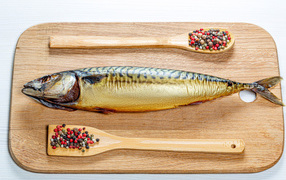 Копченая скумбрия на разделочной доске с перцем на белом фоне