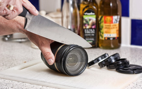 Мужчина нарезает ножом объектив фотоаппарата 