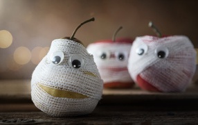 Груши и яблоки в бинтах на столе 