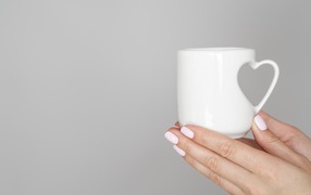 Белая кружка в руках девушки на сером фоне