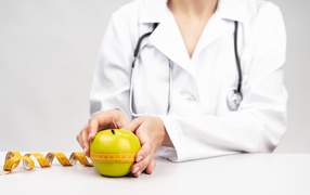 Женщина врач измеряет яблоко сантиметром 