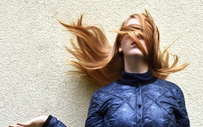 Девушка с волосами на лице стоит у стены