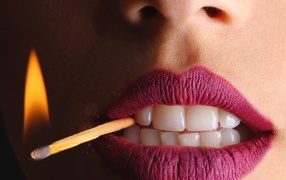Зажженная спичка в зубах у девушки 