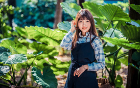 Улыбающаяся девушка азиатка в черном платье стоит в парке