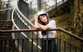 A young Asian girl stands on the stairs at the railing.