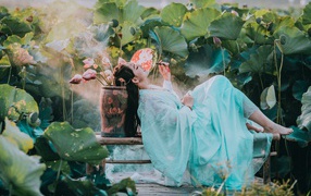 Девушка азиатка в красивом голубом платье на поле лотосов