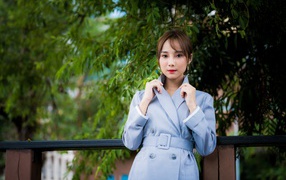 Девушка азиатка в голубом пальто в парке