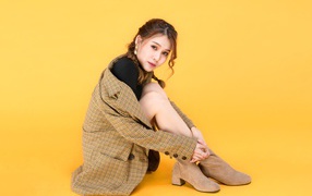 Девушка азиатка в пальто на желтом фоне 