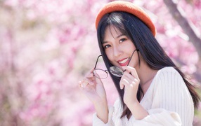 Девушка азиатка в красном берете с очками в руках