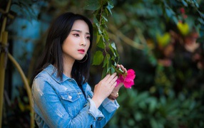 Девушка азиатка в джинсовой куртке в парке