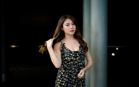 Девушка азиатка в платье трогает волосы 