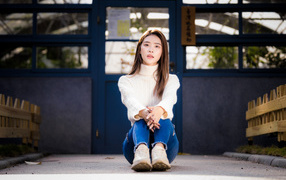 Девушка азиатка в белом свитере видит на полу 