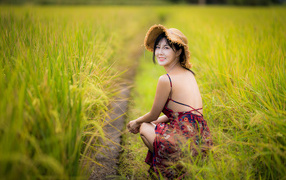 Девушка азиатка сидит на рисовом поле 