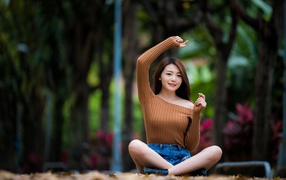 Девушка азиатка сидит в позе лотоса в парке 