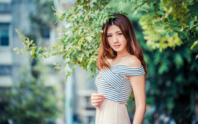 Девушка азиатка стоит под деревом в парке 