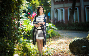 Девушка азиатка идет по улице у забора